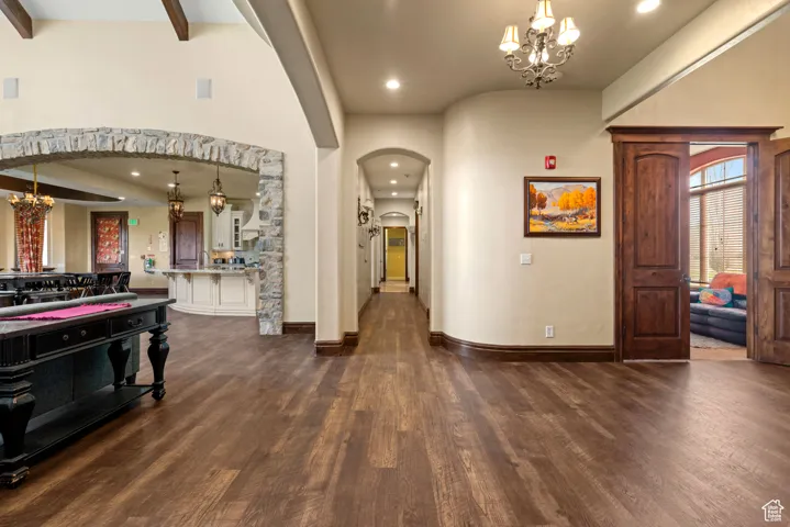 Entrance foyer with dark wood-style flooring, recessed lighting, arched walkways, and a notable chandelier
