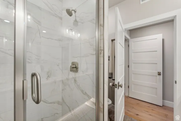 Full bathroom with toilet, a stall shower, and wood finished floors