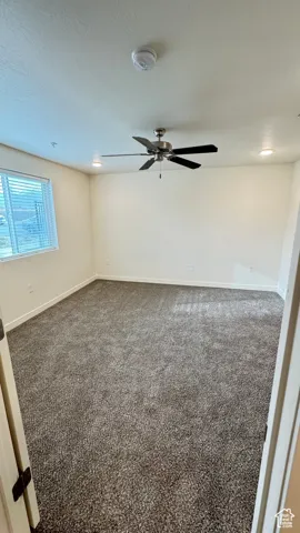 Empty room with carpet floors, baseboards, and a ceiling fan