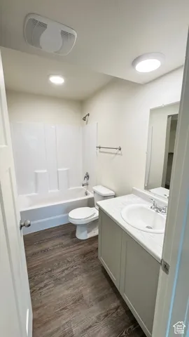 Bathroom with visible vents, toilet, vanity, wood finished floors, and shower / bathtub combination