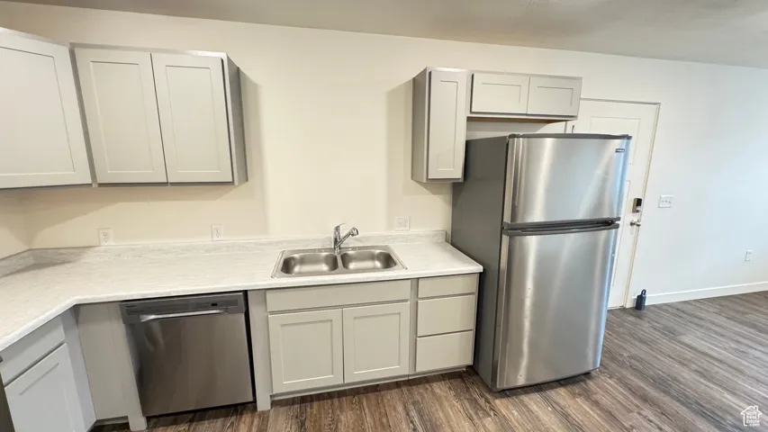 Kitchen with light countertops, a sink, dark wood finished floors, and stainless steel appliances
