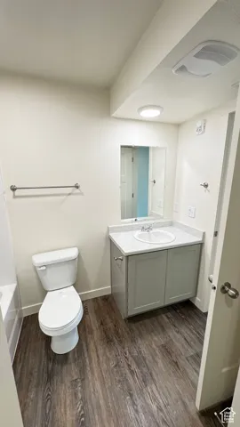 Bathroom featuring baseboards, toilet, a bathtub, vanity, and wood finished floors
