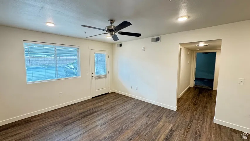 Empty room with visible vents, baseboards, ceiling fan, and dark wood finished floors