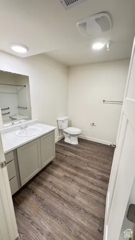 Bathroom with toilet, wood finished floors, vanity, and baseboards