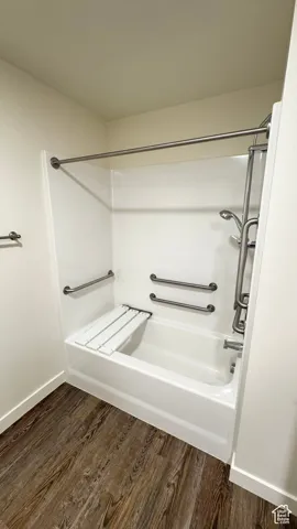 Bathroom with wood finished floors, shower / tub combination, and baseboards