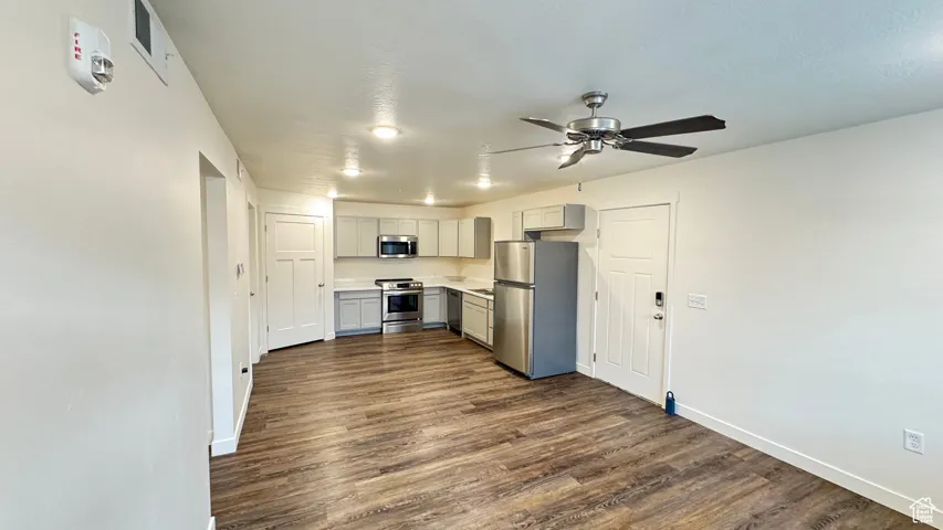 Kitchen featuring dark wood-style floors, light countertops, a ceiling fan, gray cabinetry, and stainless steel appliances