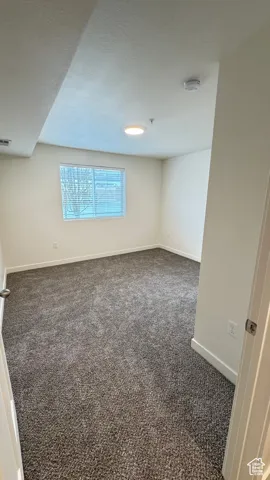 Empty room featuring carpet flooring, visible vents, and baseboards