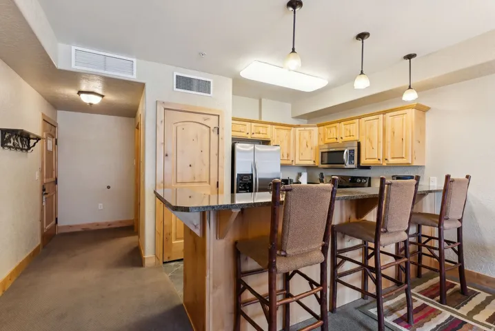 Kitchen featuring light wood cabinetry, stainless steel appliances, and a breakfast bar with stone-finish countertops