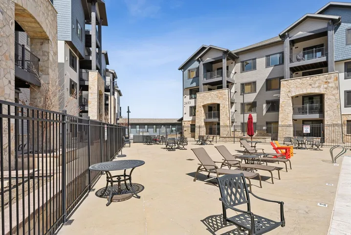 Concrete patio area surrounded by multi-level buildings featuring stone and siding exteriors