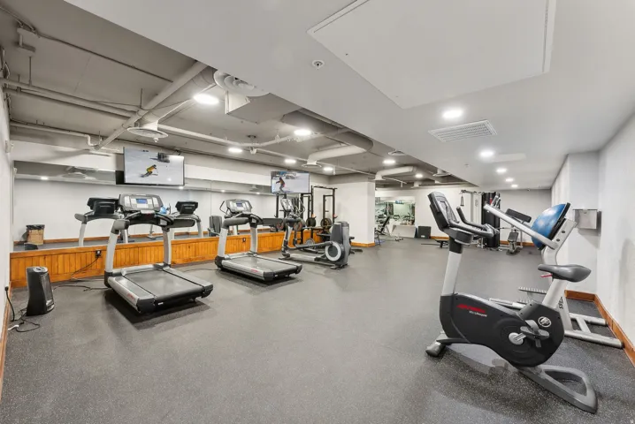 Dedicated fitness center featuring rubber flooring and mirrored walls