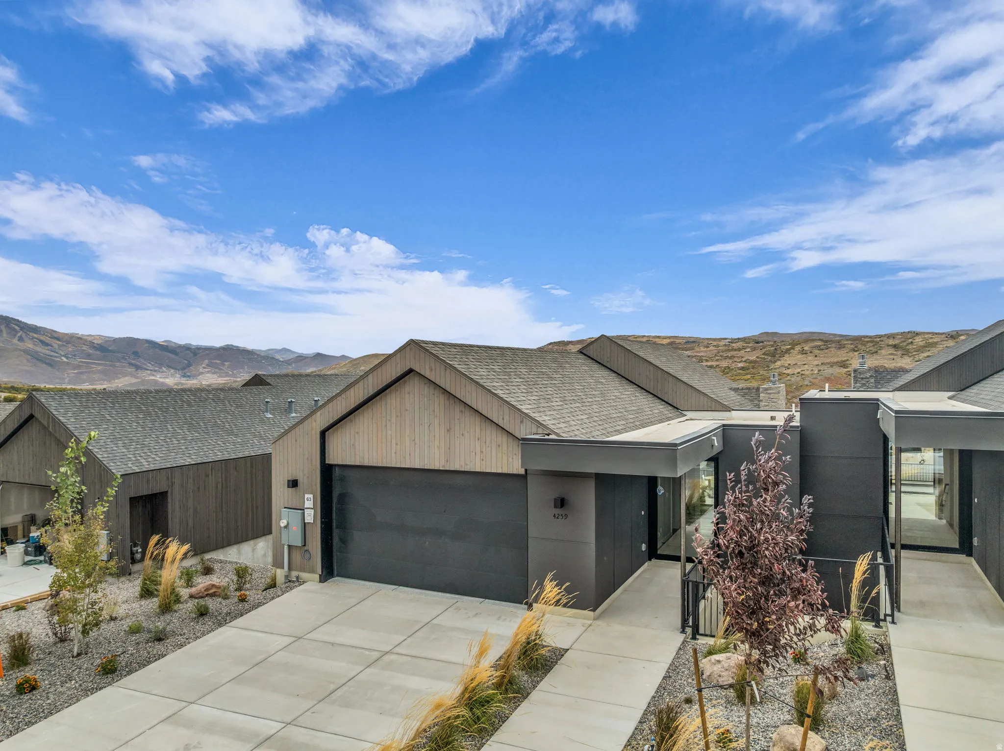 View of front of house featuring a mountain view, an attached garage, concrete driveway, and roof with shingles