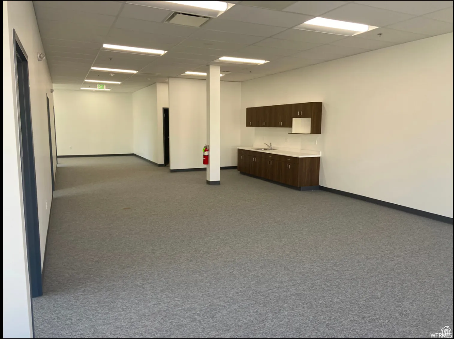 Carpeted spare room with a sink, visible vents, baseboards, and a paneled ceiling