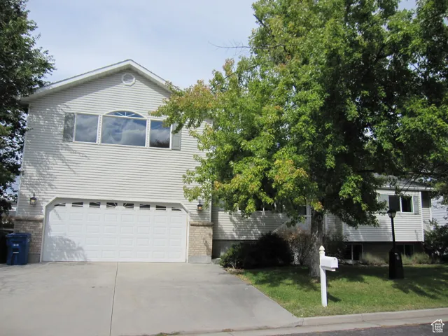 View of front facade with concrete driveway, a front yard, and a garage