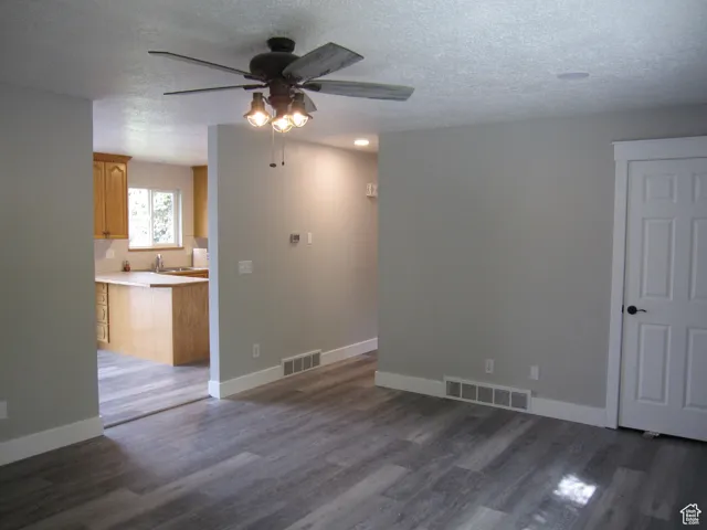 Unfurnished room with dark wood finished floors, visible vents, baseboards, and ceiling fan