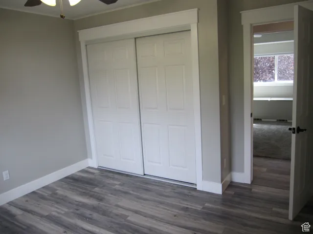 Unfurnished bedroom featuring ornamental molding, a closet, baseboards, and dark wood-style floors