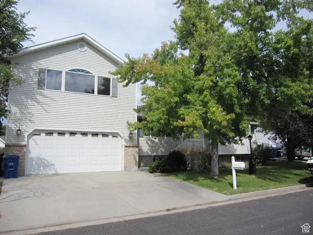 View of front of home with an attached garage, concrete driveway, and a front yard