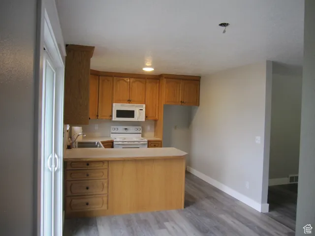 Kitchen with visible vents, a sink, light countertops, light wood-type flooring, and white appliances