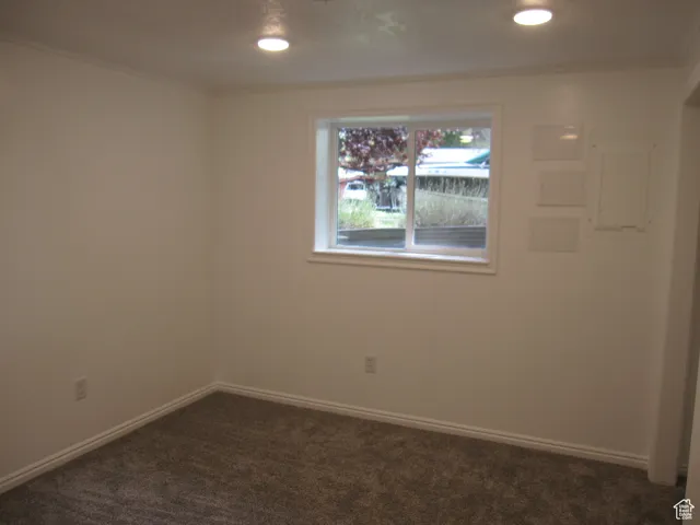 Empty room featuring crown molding, baseboards, recessed lighting, and dark colored carpet