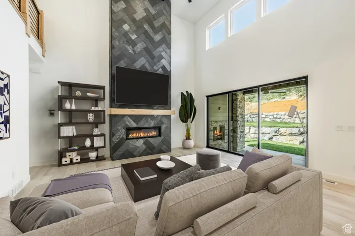 Living room featuring a high ceiling, wood finished floors, a tiled fireplace, and baseboards