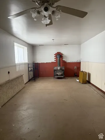 Interior space featuring a wood stove, unfinished concrete flooring, and ceiling fan