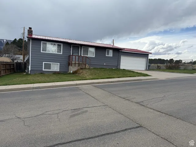 Single story home featuring a chimney, driveway, metal roof, fence, and a garage