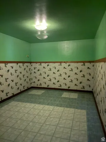 Empty room with a wainscoted wall and wallpapered walls