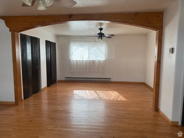 Interior space featuring arched walkways, baseboards, light wood finished floors, and baseboard heating