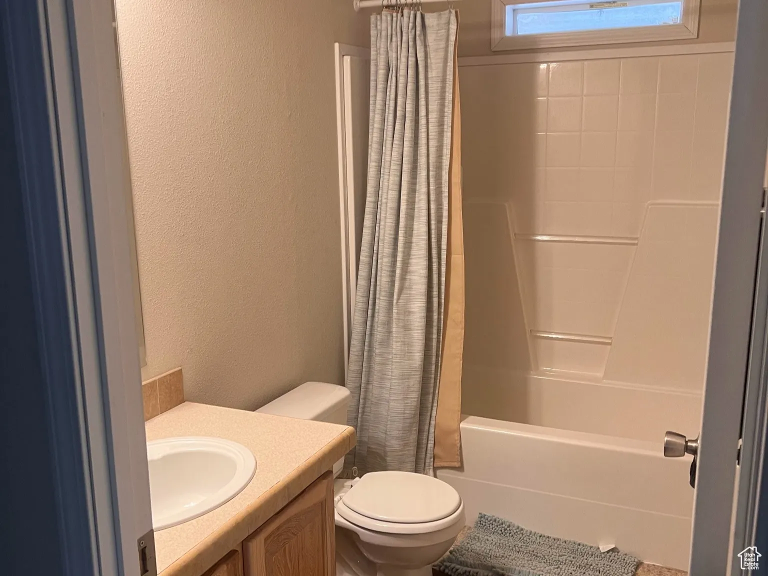 Full bath with shower / bathtub combination with curtain, toilet, a textured wall, and vanity