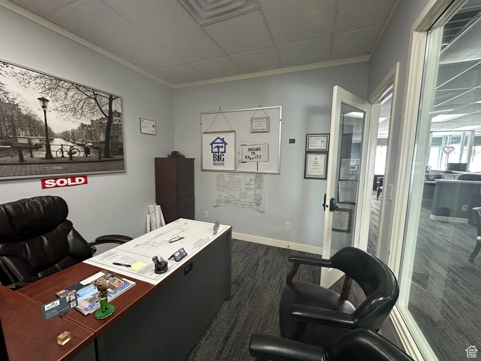 Office space with baseboards, crown molding, and dark colored carpet