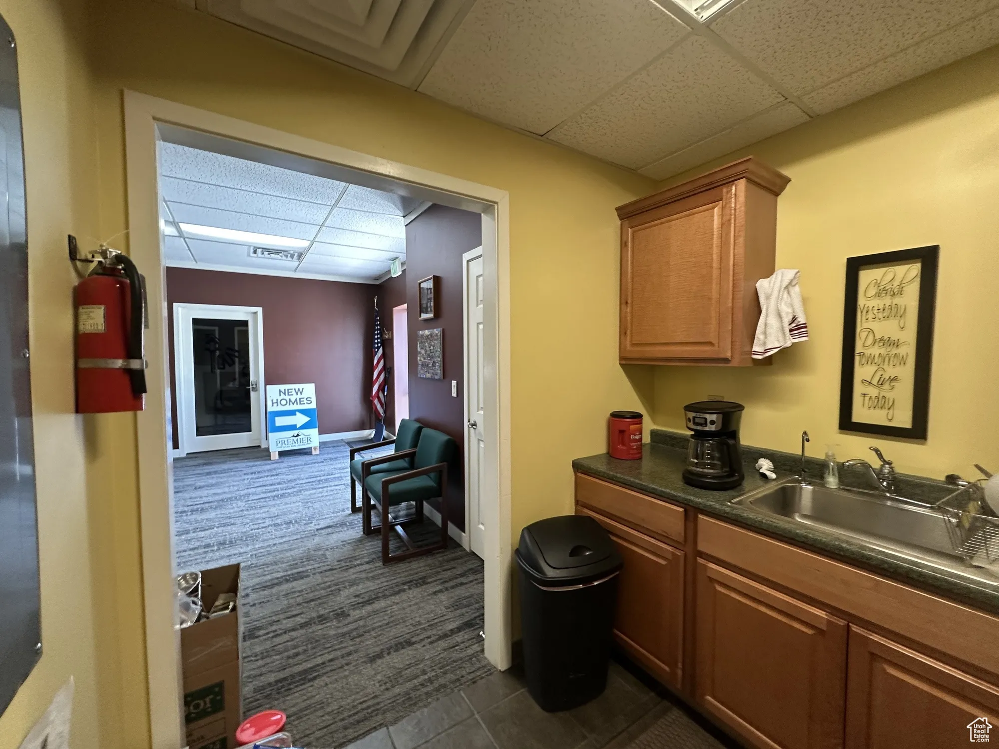 Interior space with a sink, dark carpet, dark tile patterned floors, visible vents, and a paneled ceiling