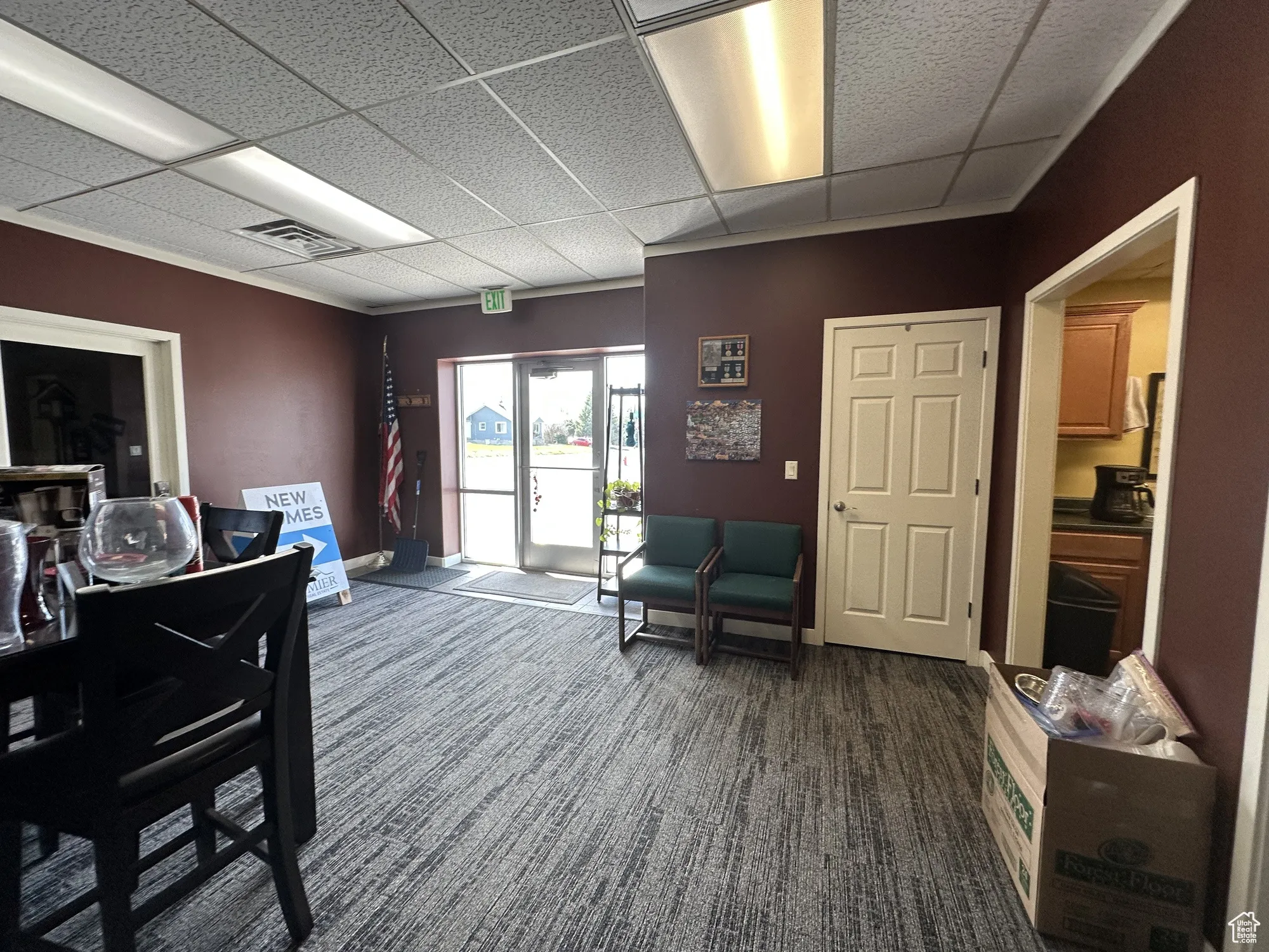 Interior space with baseboards, dark colored carpet, visible vents, and a paneled ceiling