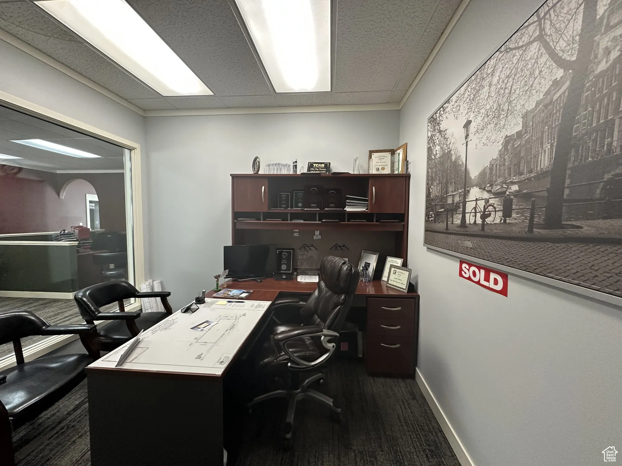 Office with dark carpet and baseboards