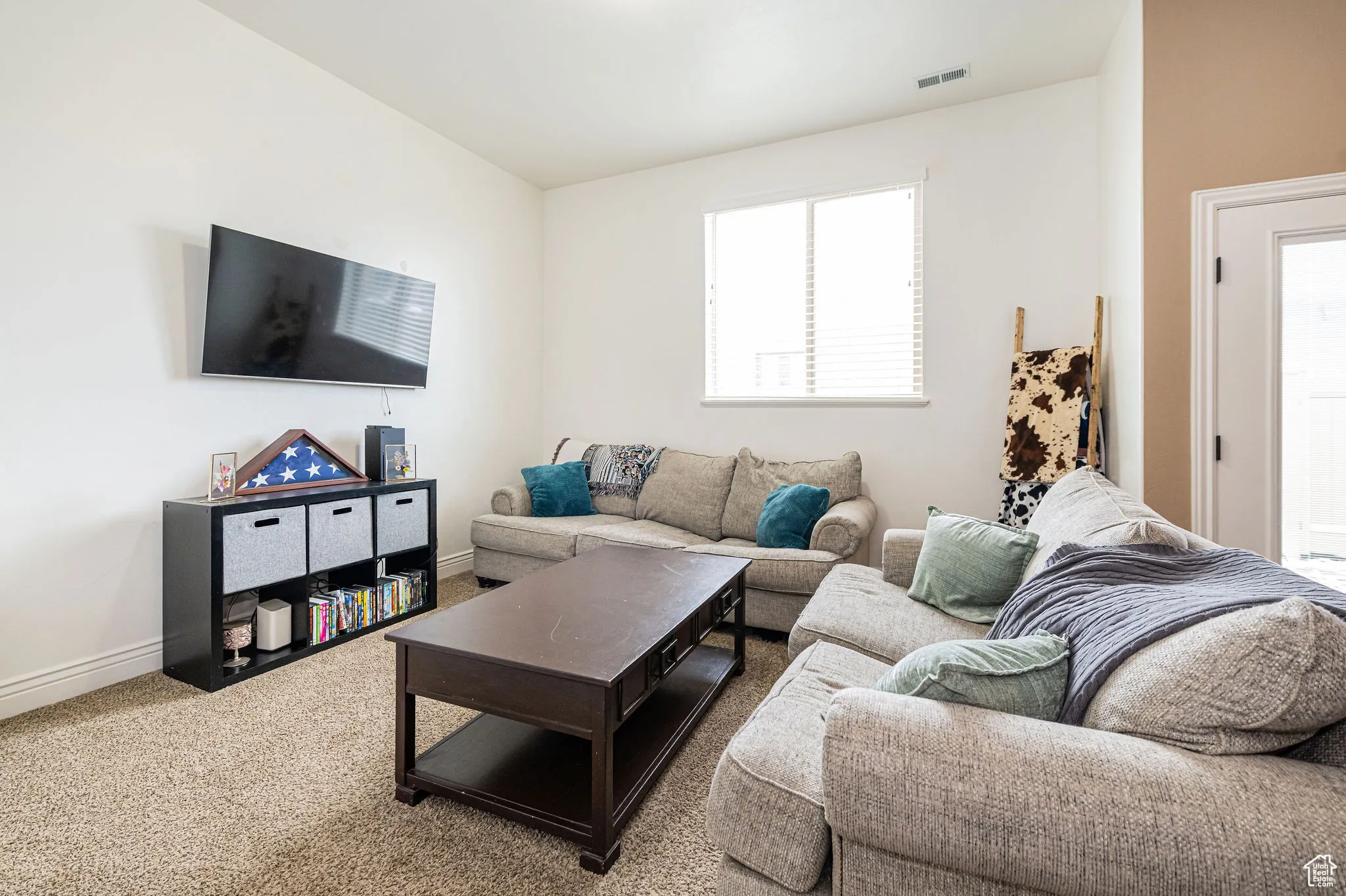 Carpeted living room with baseboards and visible vents