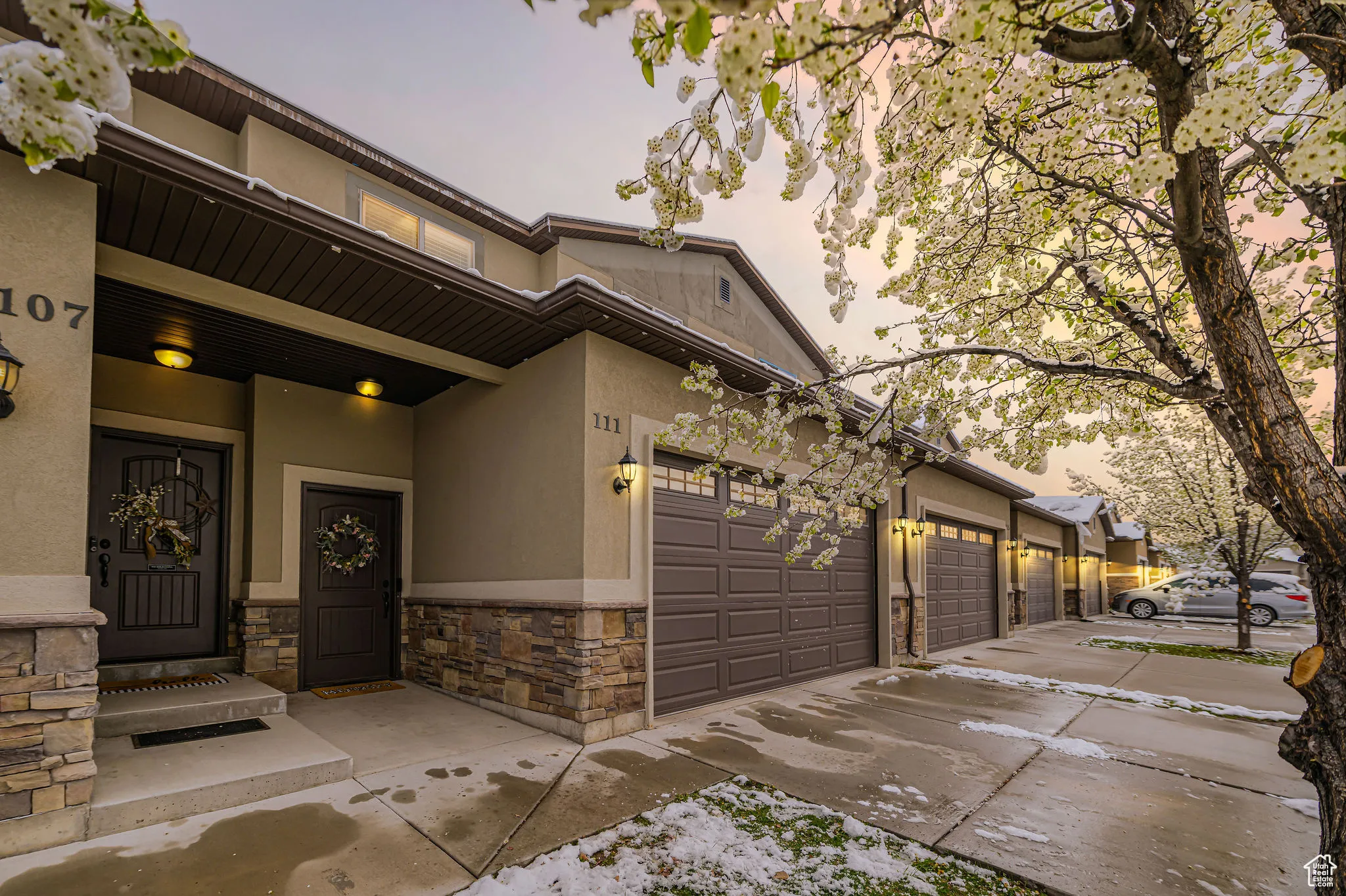View of front facade with stucco siding, driveway, stone siding, and a garage