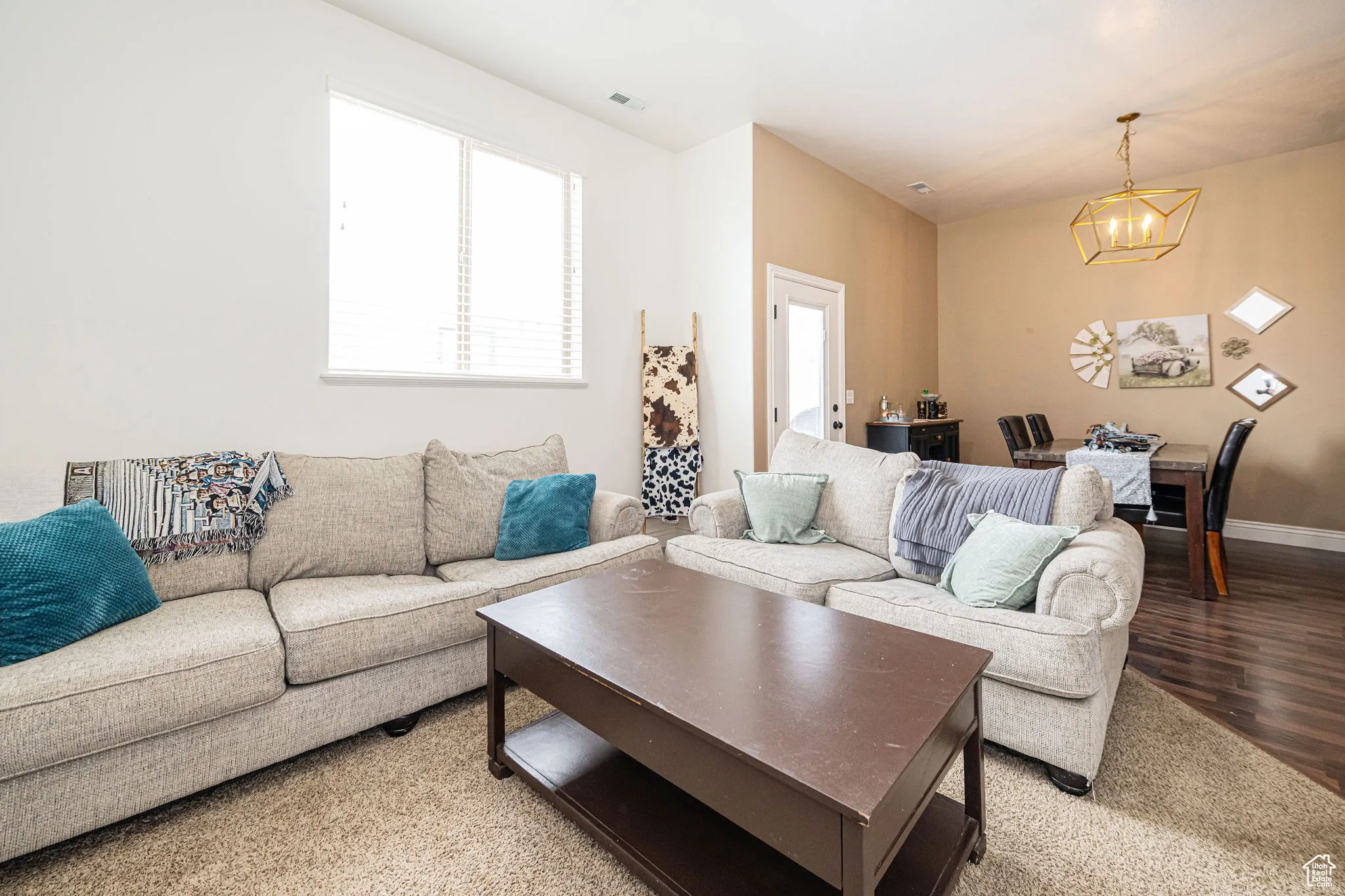 Living area with baseboards, visible vents, an inviting chandelier, and light wood-style floors