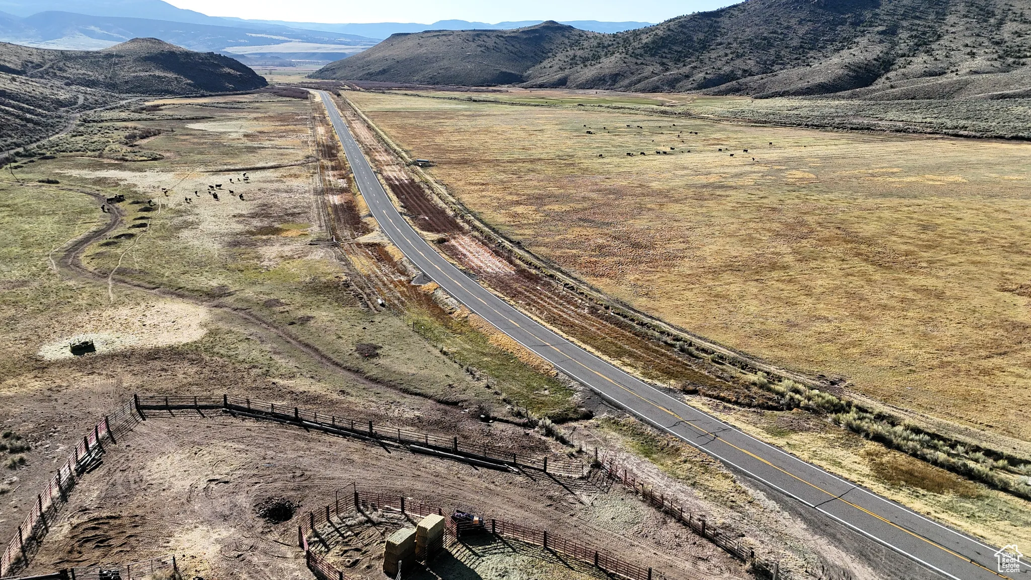 Aerial view of sparsely populated area with a mountainous background and a major roadway