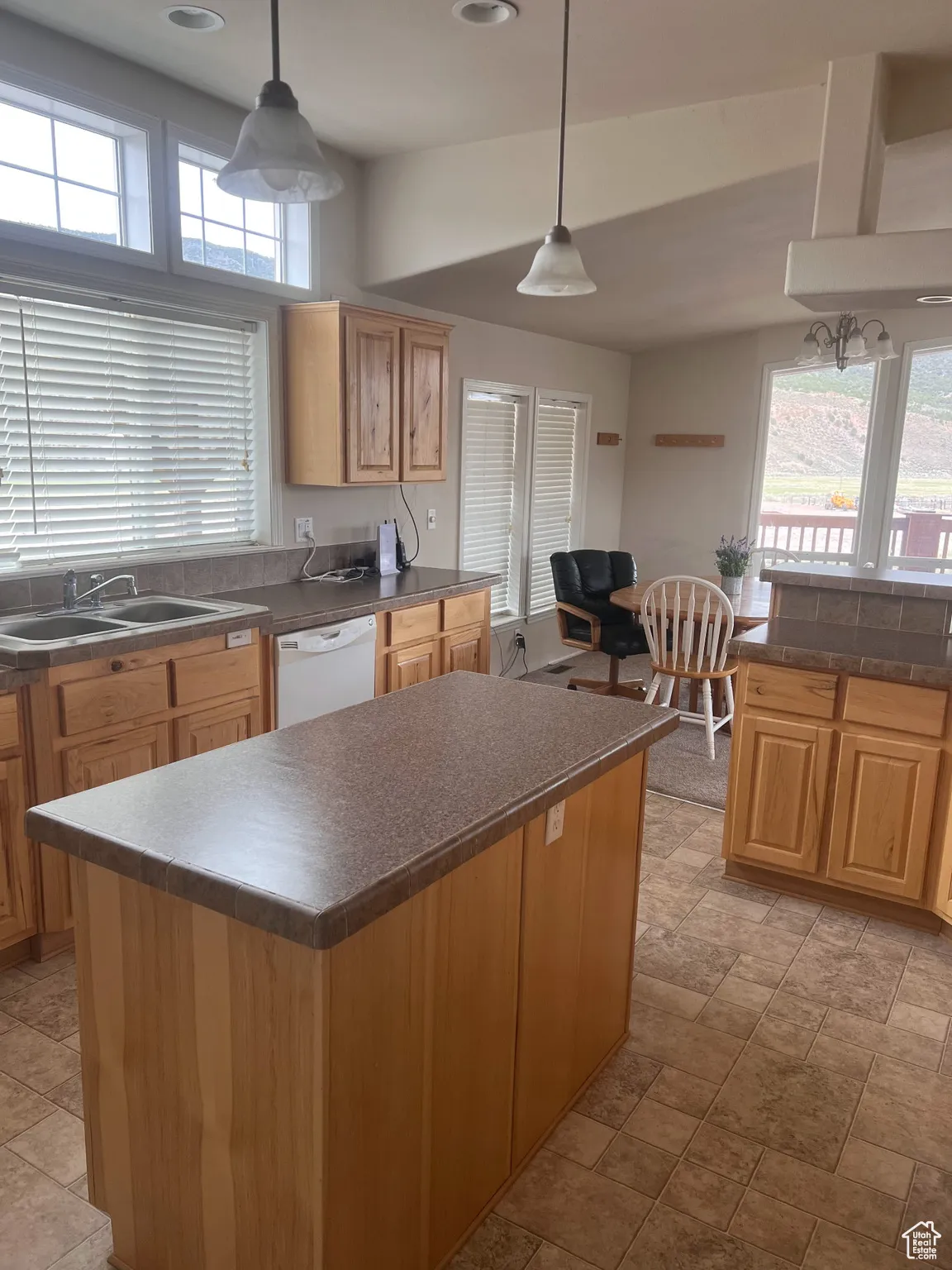 Kitchen with dark countertops, white dishwasher, plenty of natural light, a sink, and recessed lighting