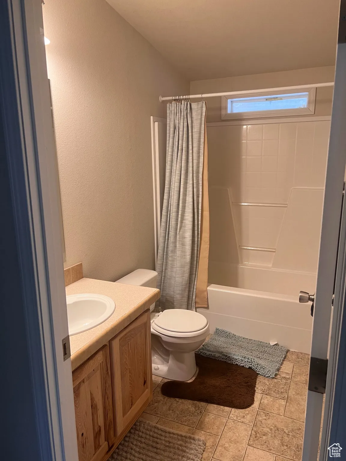 Bathroom with toilet, shower / bath combo, vanity, and a textured wall