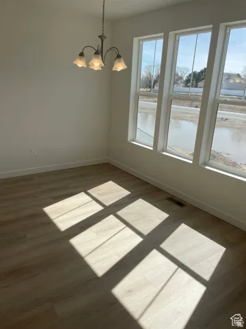 Unfurnished dining area featuring plenty of natural light, baseboards, visible vents, and a chandelier