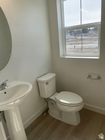 Bathroom with wood finished floors, toilet, and baseboards
