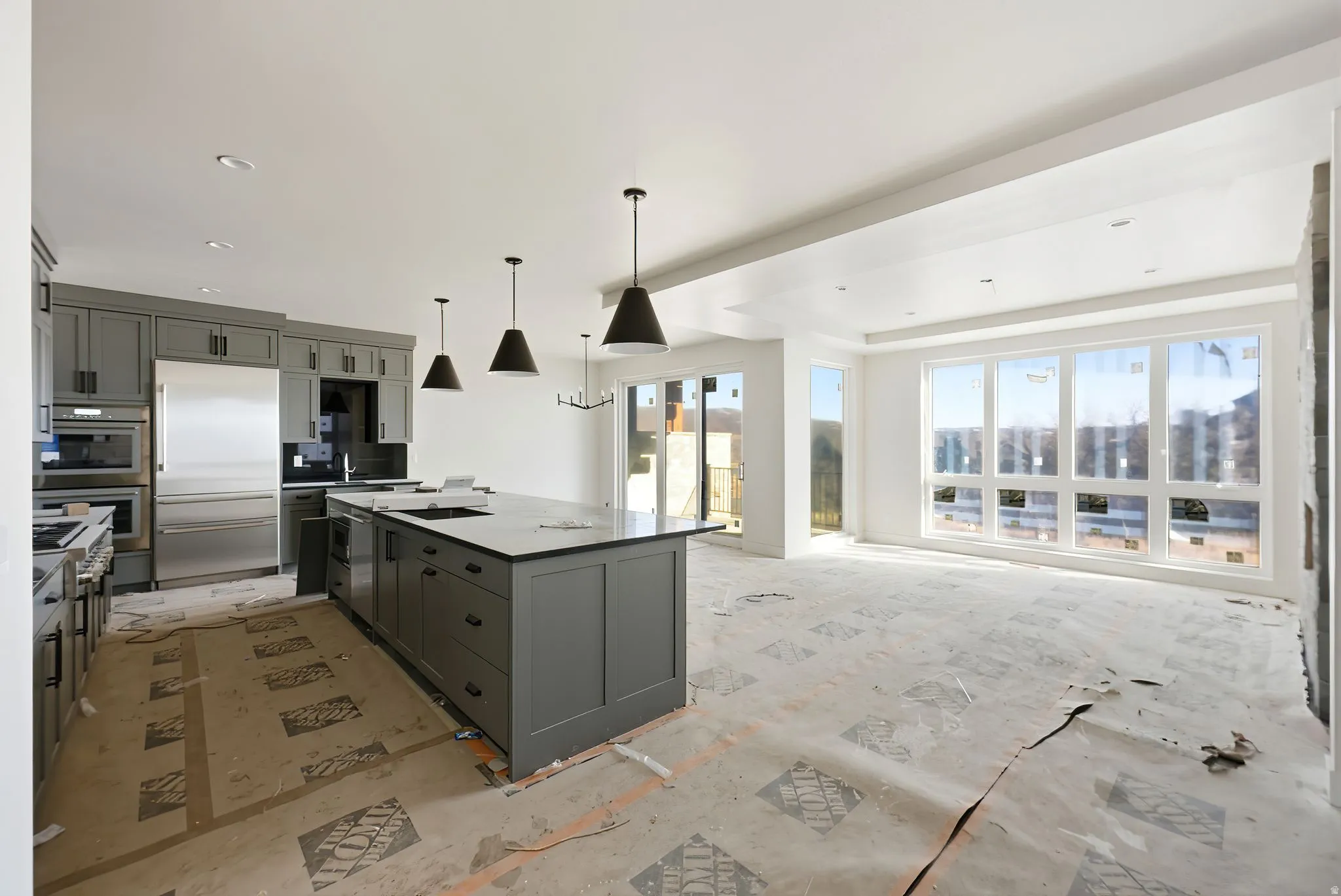 Kitchen featuring hanging light fixtures, stainless steel appliances, a kitchen island, open floor plan, and light stone countertops