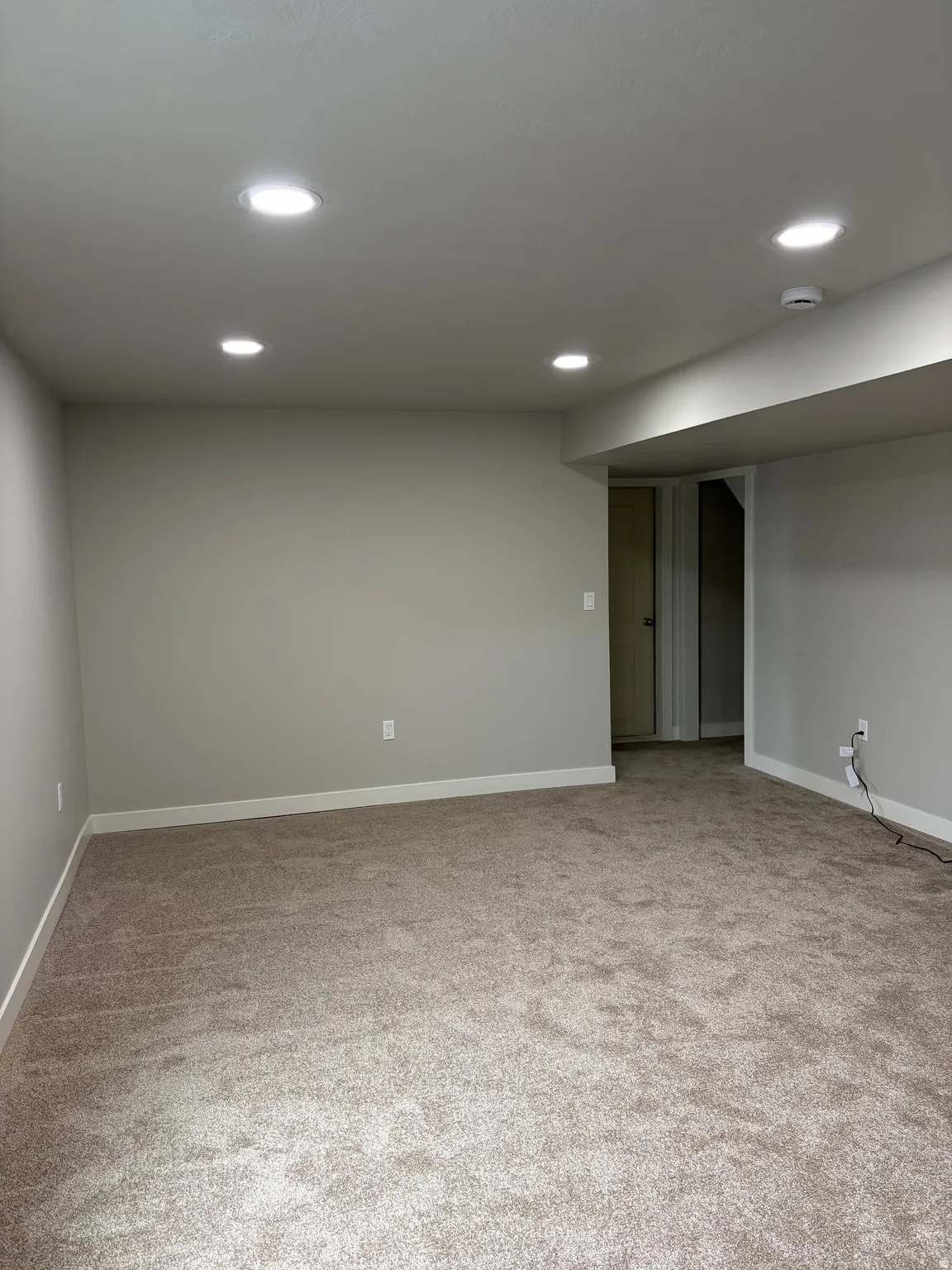 Finished below grade area with light colored carpet and recessed lighting