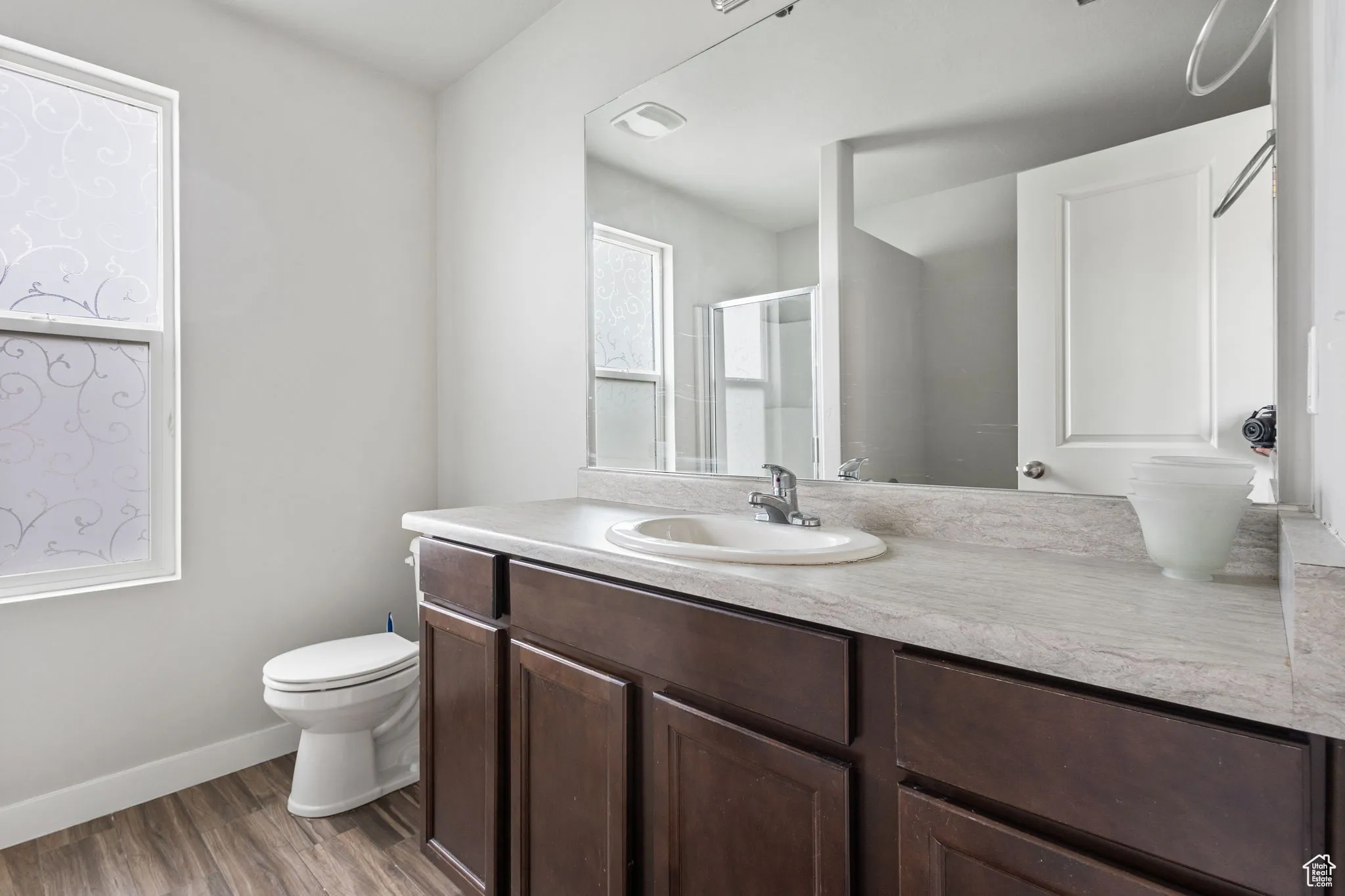 Bathroom featuring vanity, a stall shower, and wood finished floors