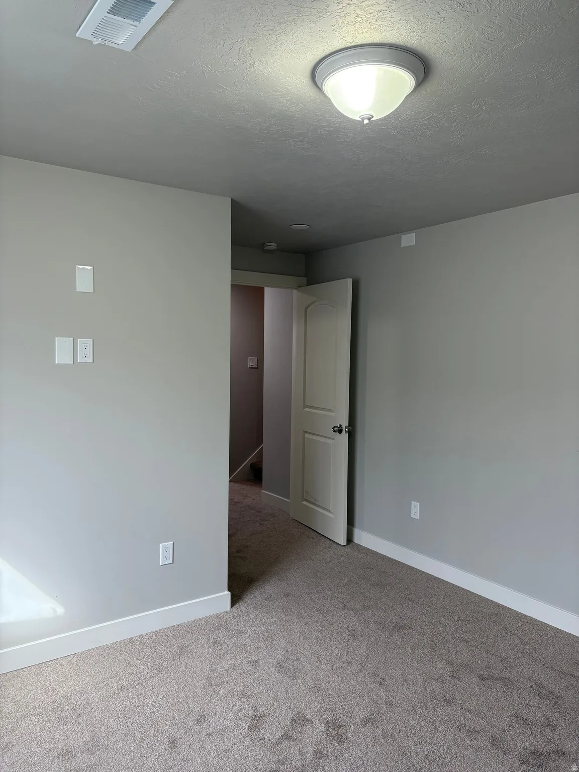 Empty room with a textured ceiling and carpet floors