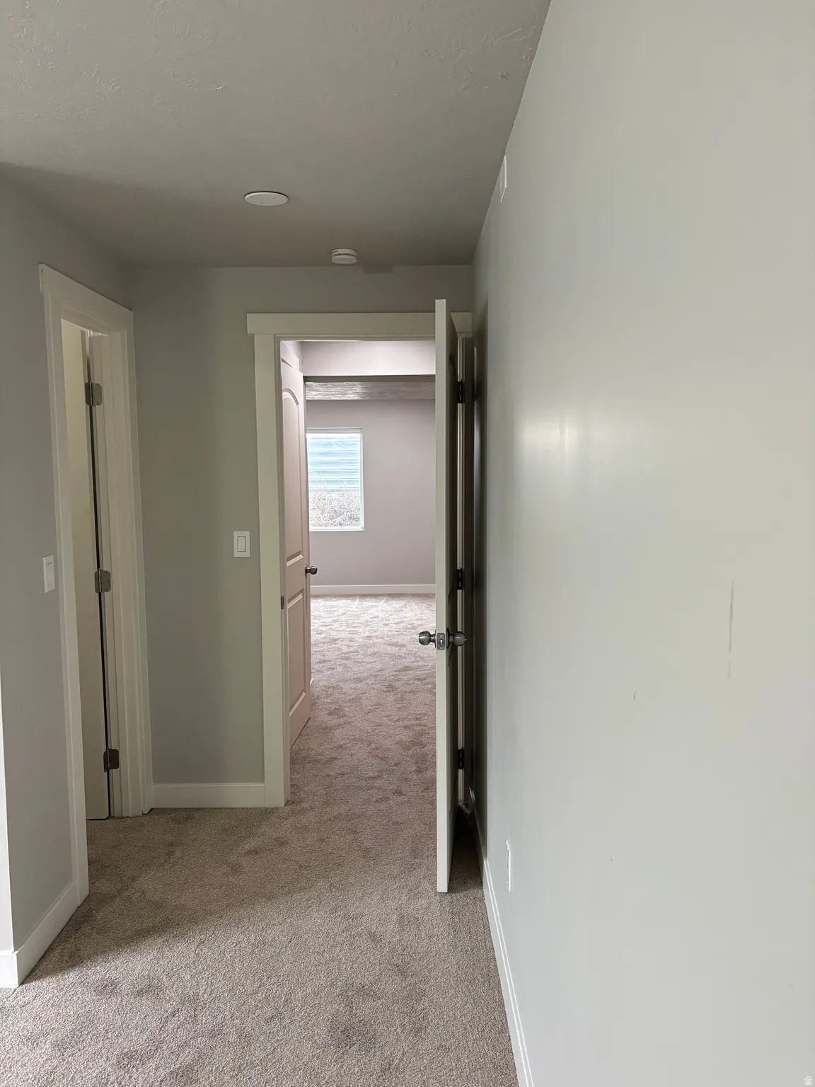Corridor with light colored carpet and baseboards