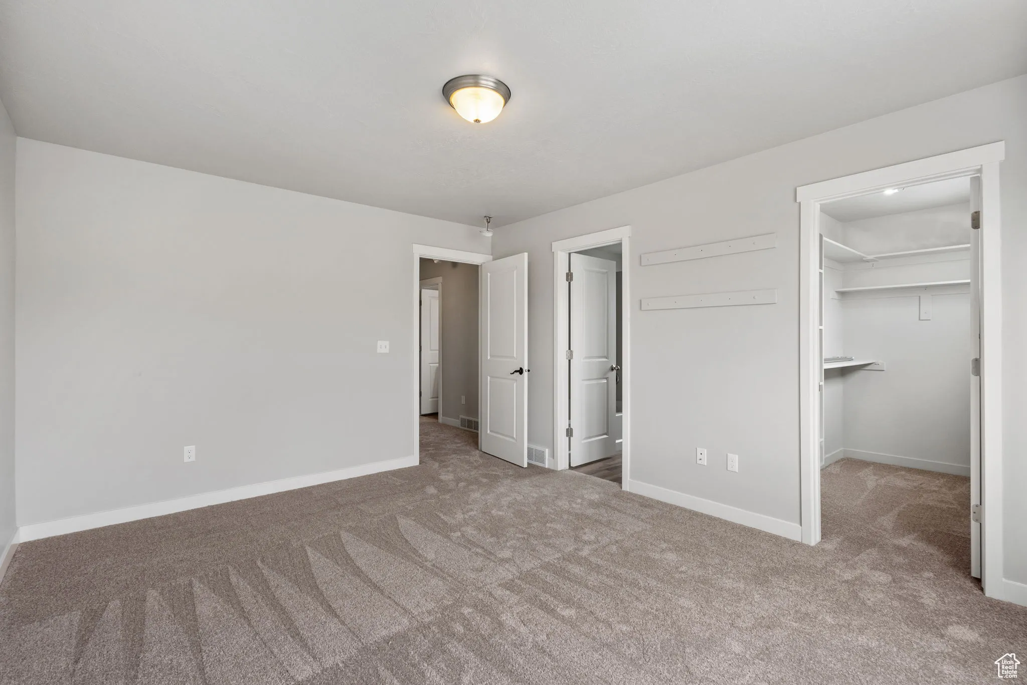 Unfurnished bedroom featuring carpet flooring and a walk in closet
