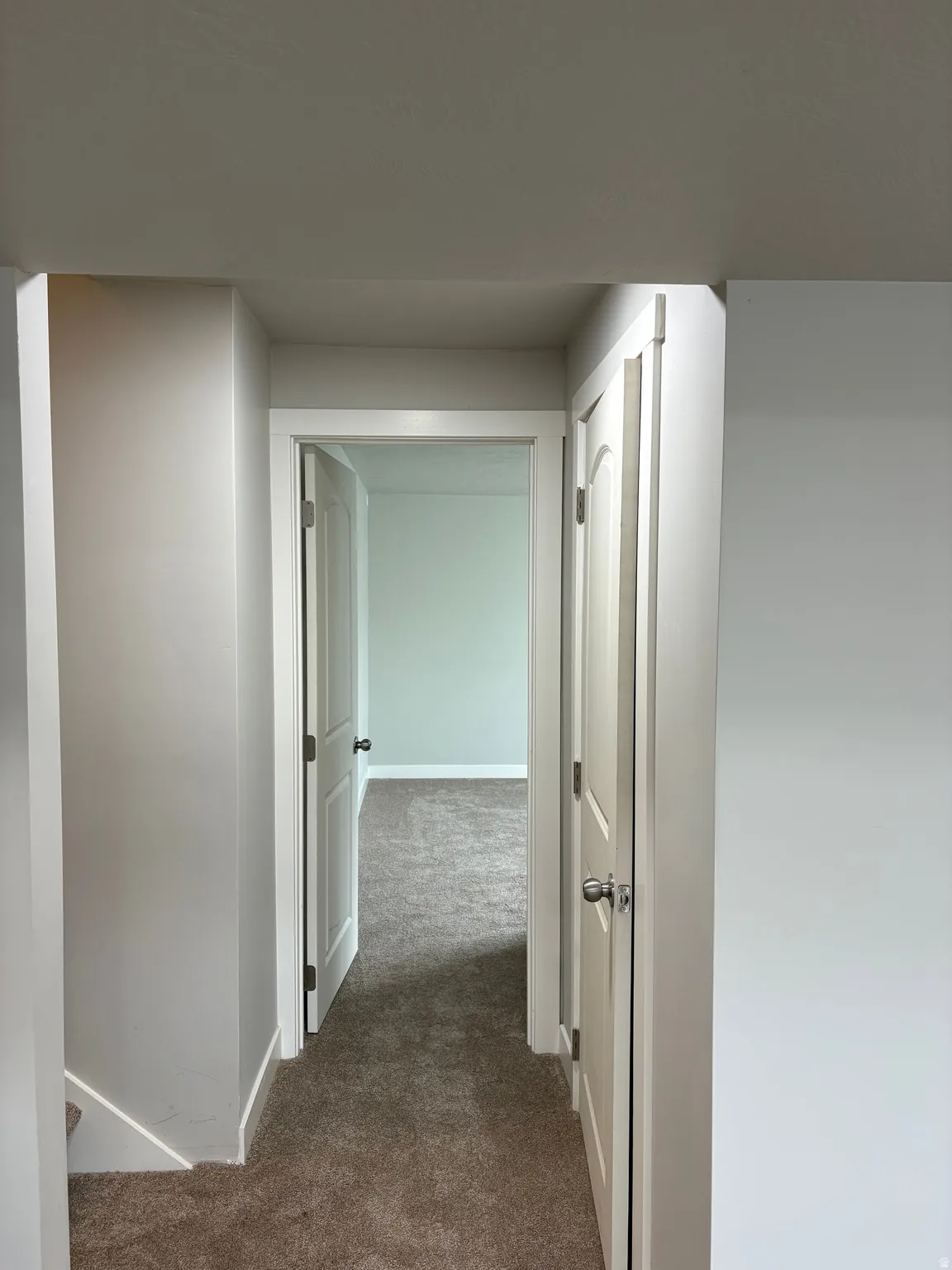 Corridor with dark colored carpet and baseboards