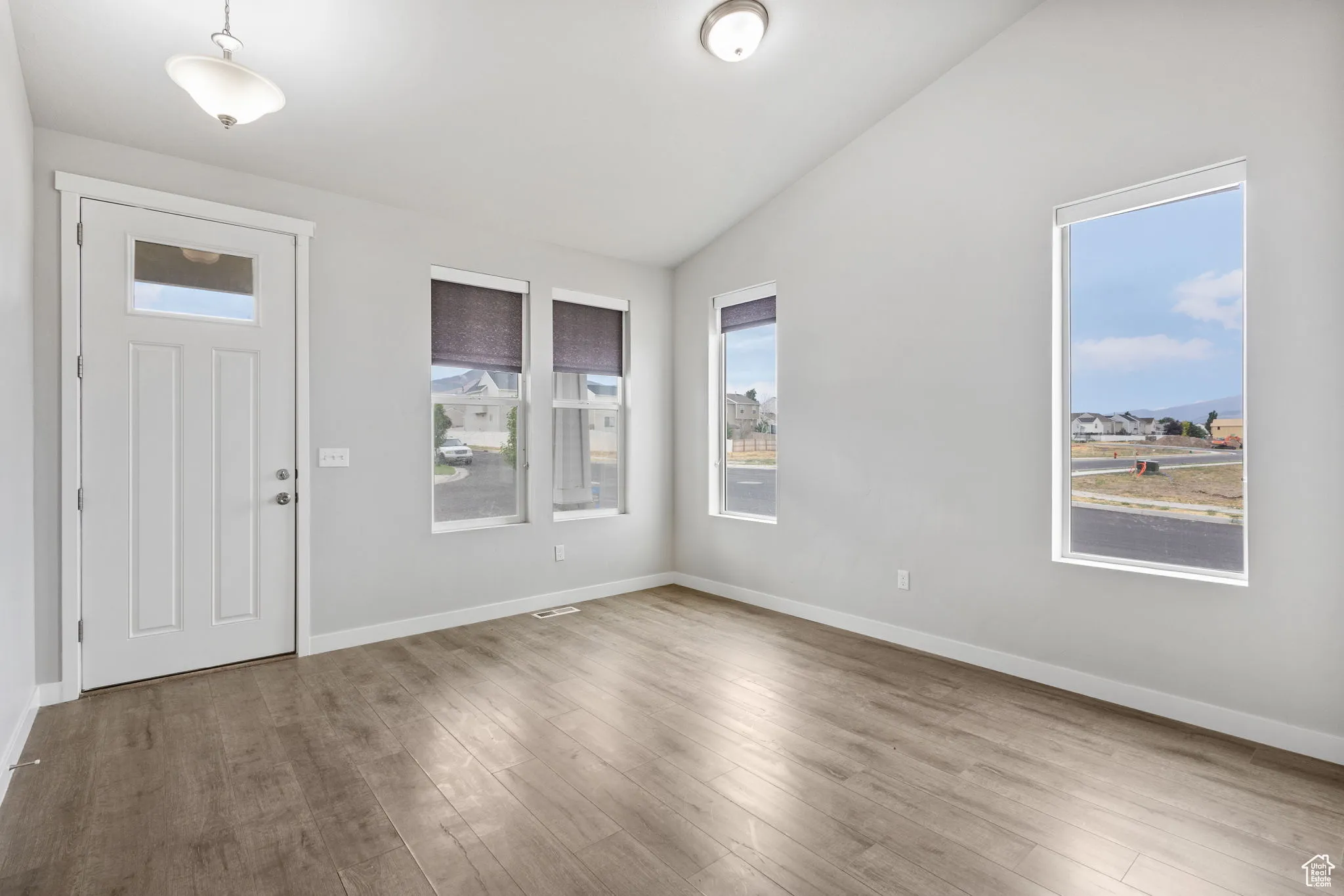 Foyer with vaulted ceiling, healthy amount of natural light, and wood finished floors