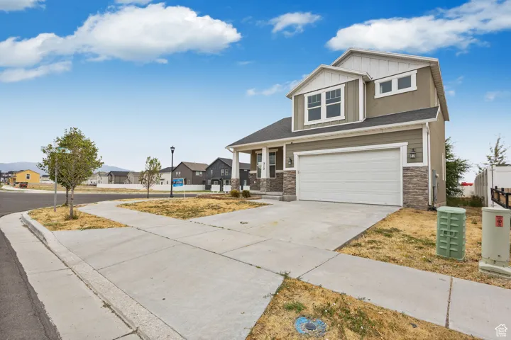 Craftsman inspired home featuring board and batten siding, a garage, driveway, and stone siding