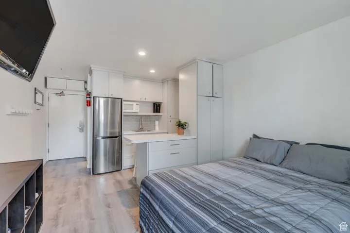 Bedroom with recessed lighting, light wood-style flooring, a sink, and freestanding refrigerator